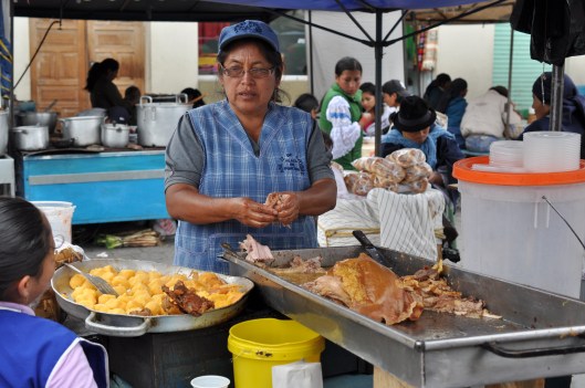 The meat the lady has in her hands in the hornado (roasted pork). The small yellow balls are mashed potatoes that are the Llapingachos.